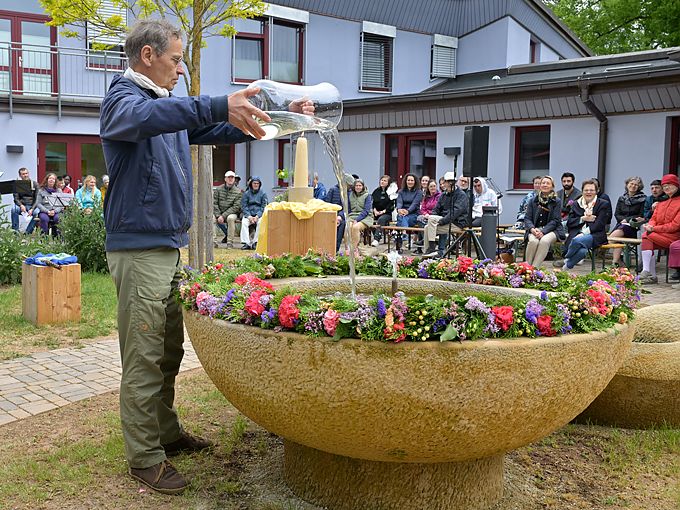 Lothar Ulrich gießt das rhythmisierte Wasser in den Brunnen und dieser begann zu sprudeln
