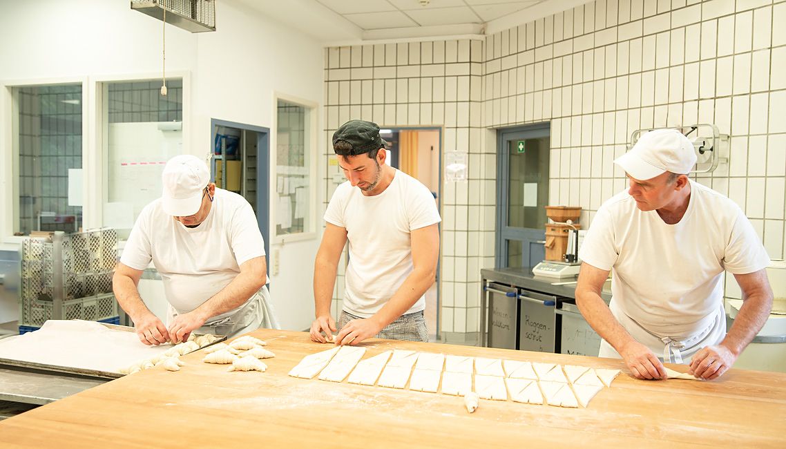 Drei Mitarbeiter rollen Croissants
